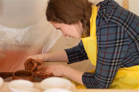 Woman Moulding Clay On Pottery Wheel Making Pot In Workshop Stock