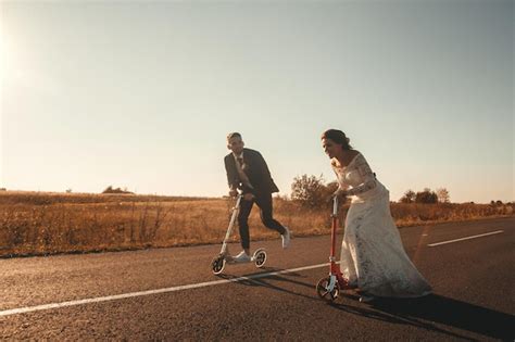 Pareja De Novios Sonriente Montando En Scooters A Lo Largo De La