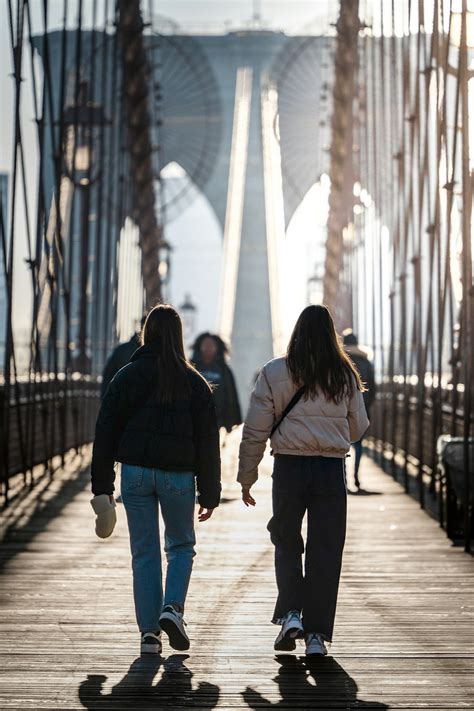 A Couple Of People Walking Across A Bridge Photo Free Brooklyn Bridge