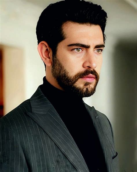 A Man With A Beard Wearing A Suit And Black Turtle Neck Sweater Looking