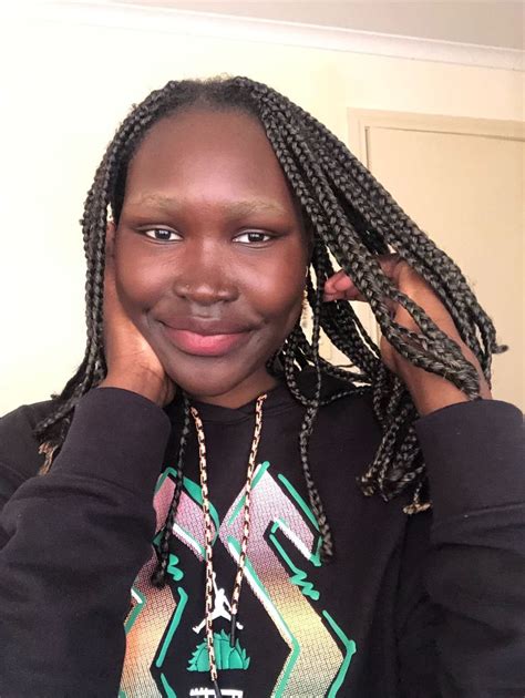 A Woman With Dreadlocks Is Smiling And Holding Her Hair In Front Of Her