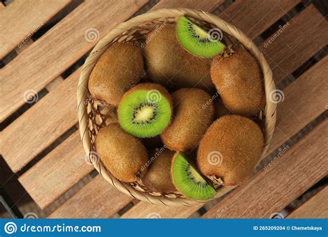 Wicker Basket With Whole And Cut Kiwis On Wooden Table Top View Stock