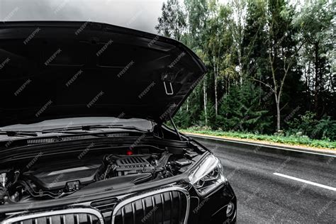 Черный автомобиль с открытой парковкой капота на дороге в дождливый ...