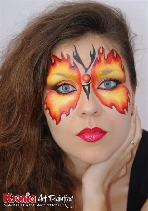 A Woman With Makeup Painted To Look Like A Firebird And Flames On Her Face