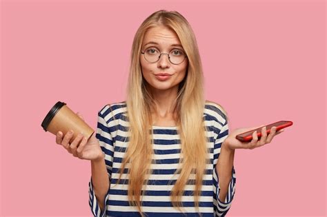 Étudiante Blonde Hésitante Posant Contre Le Mur Rose Photo Gratuite