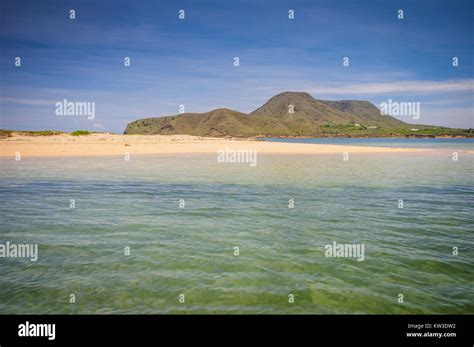 Calm ocean shore at base of mountain at Monte Cristi National Park in ...