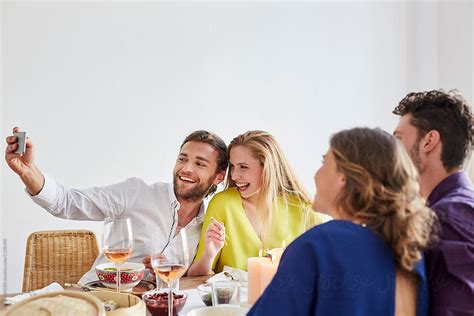 Man Taking Self Portrait With Friends At Dining Table By Stocksy Contributor Alto Images