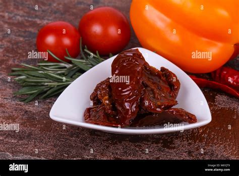 Dried Tomatoes In The Bowl With Olive Oil Served Rosemary Salad Leaves