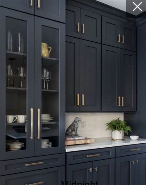 A Kitchen With Blue Cabinets And White Counter Tops Gold Pulls On The