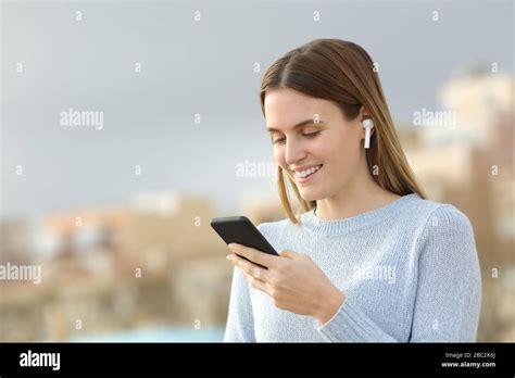 Happy Teenage Girl Wearing Wireless Earbuds Listening To Music Checking