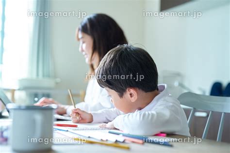 部屋で仕事をする日本人の母親と、お絵描きをする子供 （人物）の写真素材 [214326847] イメージマート