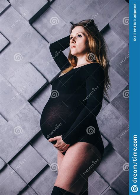 A Pregnant Woman In Lingerie With A Big Belly In The Ninth Month Of Pregnancy Is Posing Next To