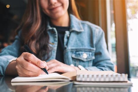 Premium Photo Midsection Of Woman Writing In Book While Sitting At Table