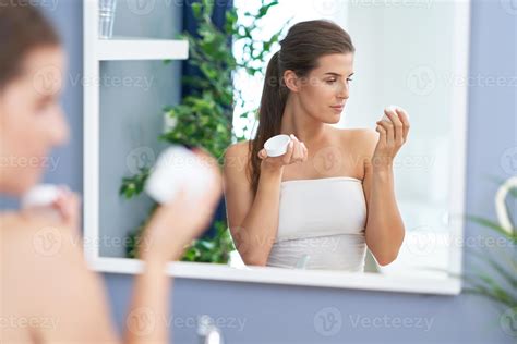 Beautiful Brunette Woman Applying Face Cream In The Bathroom Stock Photo At Vecteezy