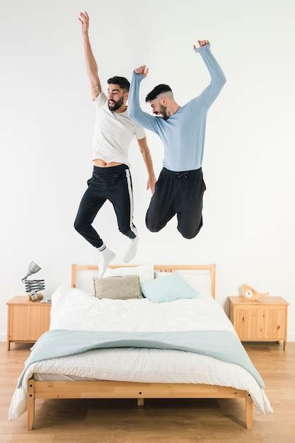 Pareja Gay Saltando En La Cama En El Dormitorio Foto Gratis