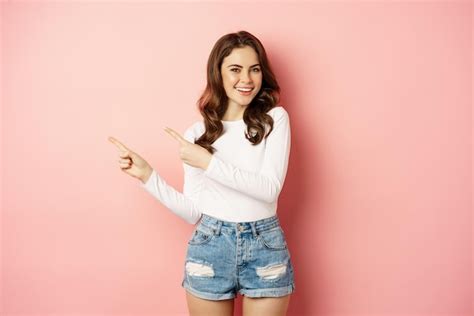 Premium Photo Cute Smiling Brunette Girl Showing Advertisement Pointing Fingers Left At