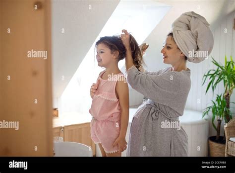 Portrait Of Pregnant Woman With Small Daughter Indoors In Bathroom At