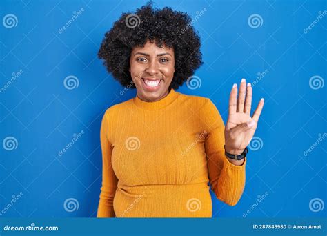 Black Woman With Curly Hair Standing Over Blue Background Showing And Pointing Up With Fingers