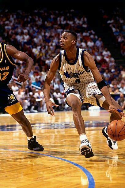 Two Men Playing Basketball On A Court With Fans In The Bleachers Behind