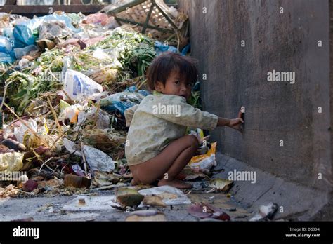 A Young Girl Is Defecating In A Dumpster Filled With Garbage On A Stock