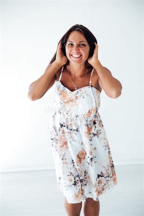 Tanned Brunette Woman In White Summer Dress Holding Her Hair With Her Hands And Smiling Stock