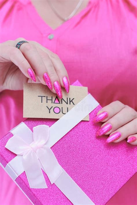 Female Hands With Long Nails And Pink Nail Polish Hold A Picture With