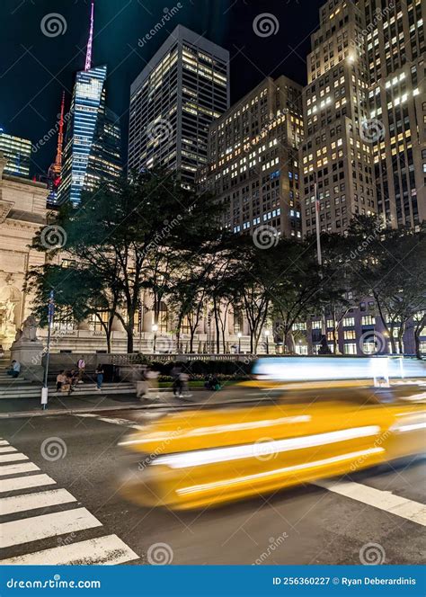 Blurred Yellow Taxi Driving Down the Street in New York City at Night