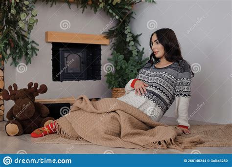 Beautiful Pregnant Woman Sitting By The Fireplace Wrapped In A Brown