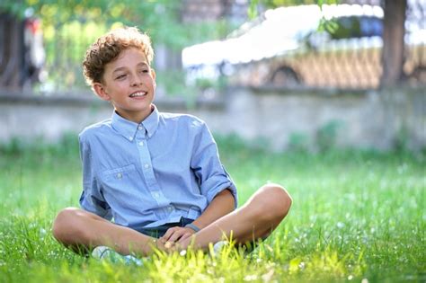 Menino criança feliz relaxante na grama verde no parque de verão