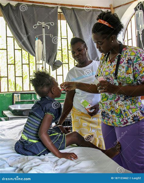 Haitian Nurse Cares For Young Patient As Mother Looks On Editorial