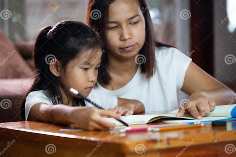 Young Asian Mother Helping Her Daughter Do Her Homework At Home Stock