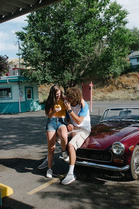 Teenage Couple Eat Burgers In Parking Lot Of Drive In By Stocksy Contributor Tana Teel Stocksy