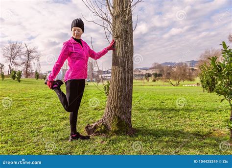 Mujer Joven Que Calienta Y Que Estira Las Piernas Antes De Correr En Un