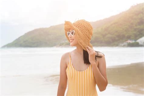 Mujer hermosa joven en bikini escuchando música y usando un teléfono inteligente en la playa