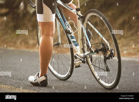 A Close Up To The Legs Of A Female Cyclist Sitting On Her Road Bike