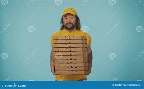 Delivery Man In Yellow Uniform Holding A Big Stack Of Pizza Boxes