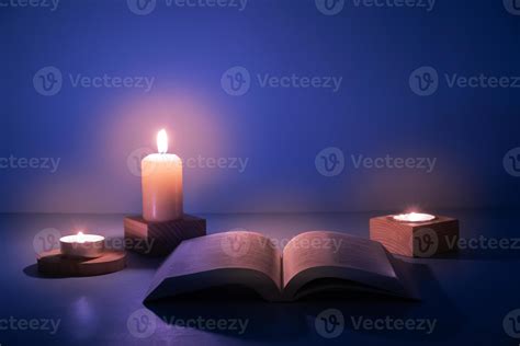 Open Christian Holy Bible With Candles Lighting On Blue Background