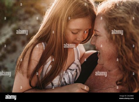 Side View Of Mother And Redheaded Elementary Age Daughter At Sunset