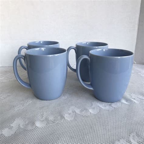 three blue coffee mugs sitting on top of a white tablecloth covered ...