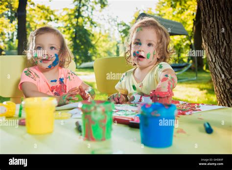 Two Year Old Girls Painting With Poster Paintings Together Against