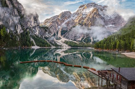 Domek i łódki na jeziorze Pragser Wildsee z widokiem na włoskie Dolomity