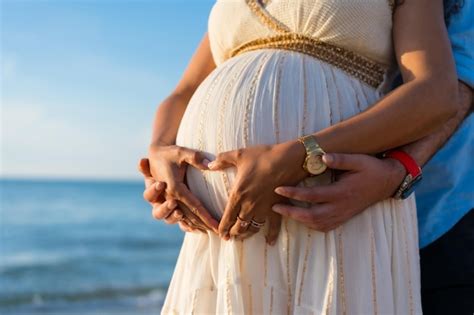 Mulher latina de maternidade grávida na praia ao pôr do sol conceito de maternidade fazendo o