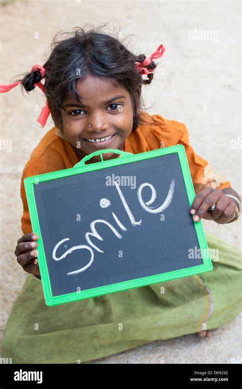 Happy Indian Street Girl Holding A Chalkboard With Smile Written On It