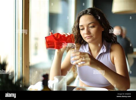 Mujer Llenando Un Vaso De Agua De Una Botella Sentada En Un Restaurante