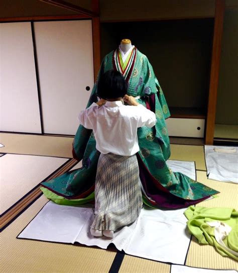 A Woman Dressing A Mannequin In Junihitoe For A Kimono Demonstration