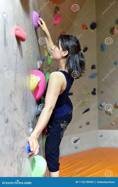 Young Sporty Pretty Woman Climbing Up A Wall In A Bouldering Ha Stock