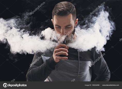 Young man vaping e-cigarette with smoke on black Stock Photo by ©Milkos ...