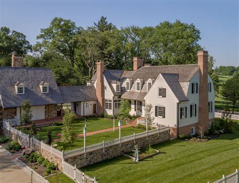 Dutch Colonial Inspired White Siding And Brick House With Attached Barn