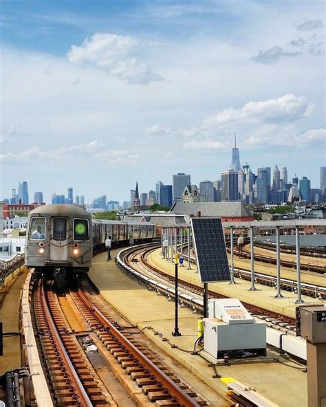 a train traveling down tracks next to a large cityscape with tall ...