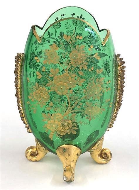 An Ornately Decorated Green Glass Vase With Gold Trimmings And Flowers